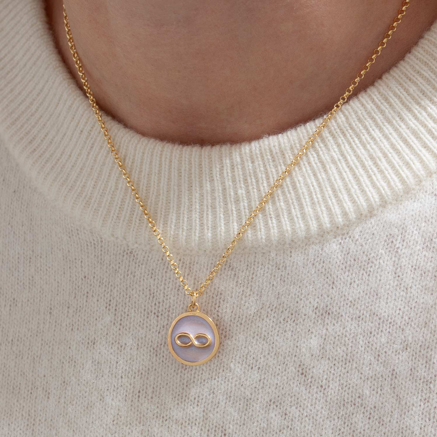 Moneta smaltata bianco perlaceo con simbolo dell'infinito sporgente. Moneta elegante dorata in argento, smaltata a mano elegante e raffinata